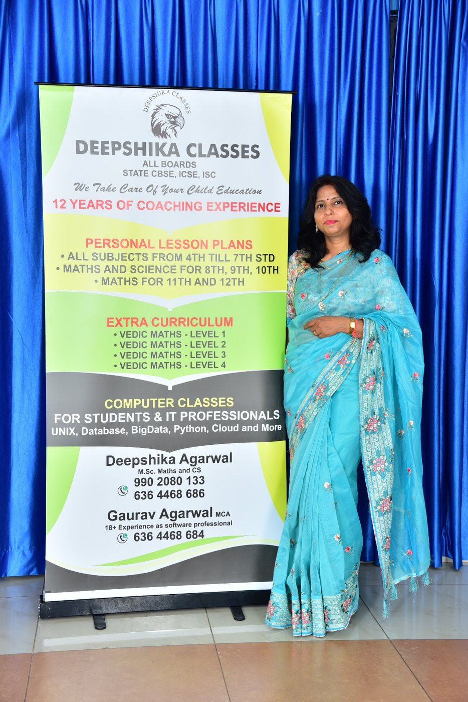 Deepshika Agarwal standing beside the Deepshika Classes banner